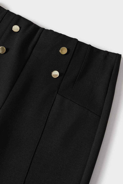 Close-up of black trouser waistband with gold buttons and tailored front panels