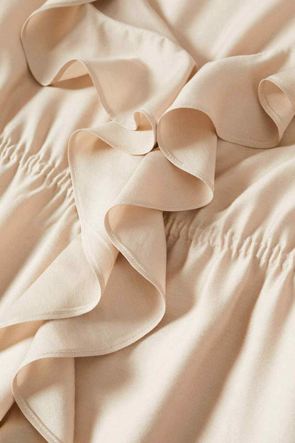 Close-up of ecru ruffle trim and gathered fabric on MANGO midi dress