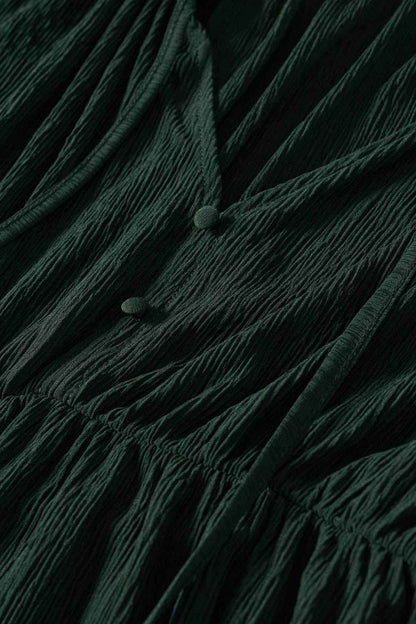 Dark green fabric close-up with textured drape and small covered buttons