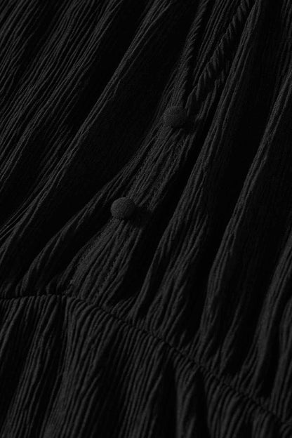 Black pleated fabric close-up with gathered seams and pom-pom trim