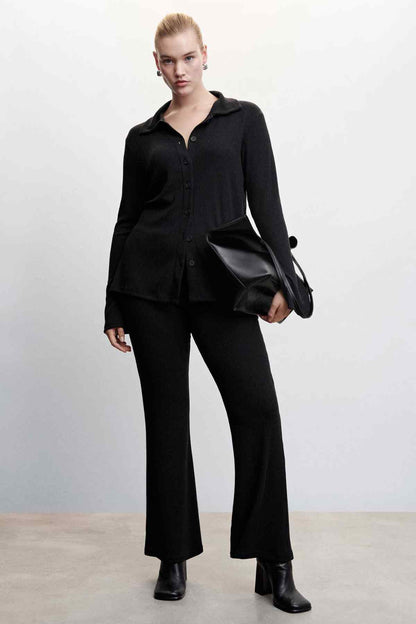 Black knit button-up jacket worn with trousers; pointed collar and front buttons