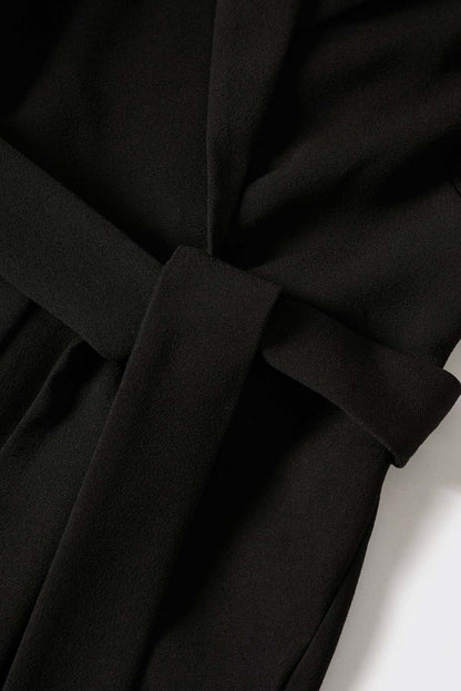 Black jumpsuit fabric close-up with lapel and tied waist detail
