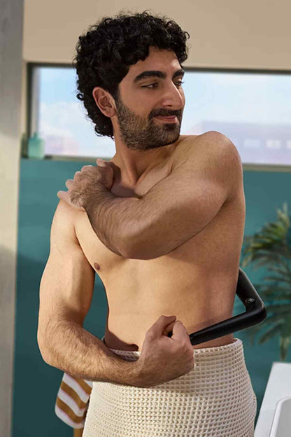 Black handheld Philips grooming trimmer with guard resting against chest