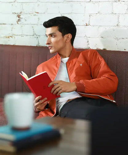 Rust-orange bomber jacket with small chest emblem and zip front