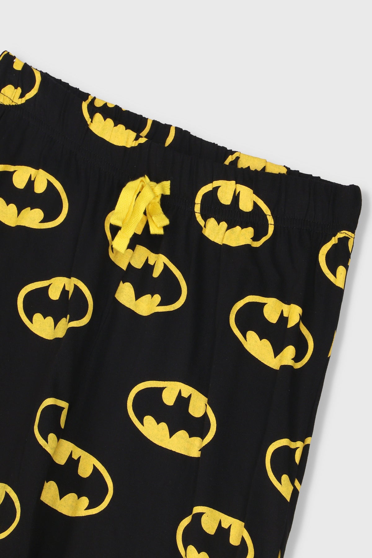 Batman pajama pants in black with repeating yellow Bat icons and elastic waist drawstring.
