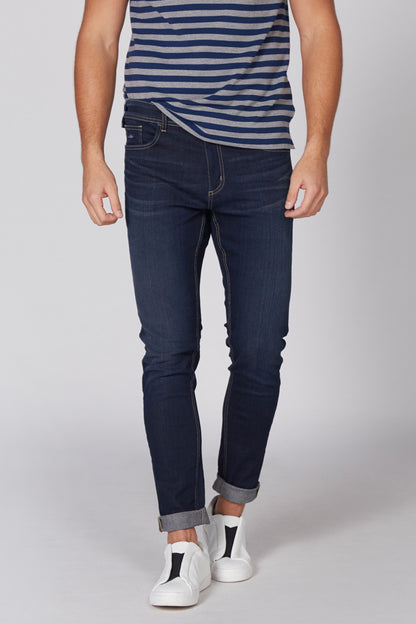 Men's blue striped polo shirt, dark jeans, and white sneakers