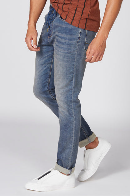 Blue denim jeans with five pockets, subtle whiskering, and rolled cuffs