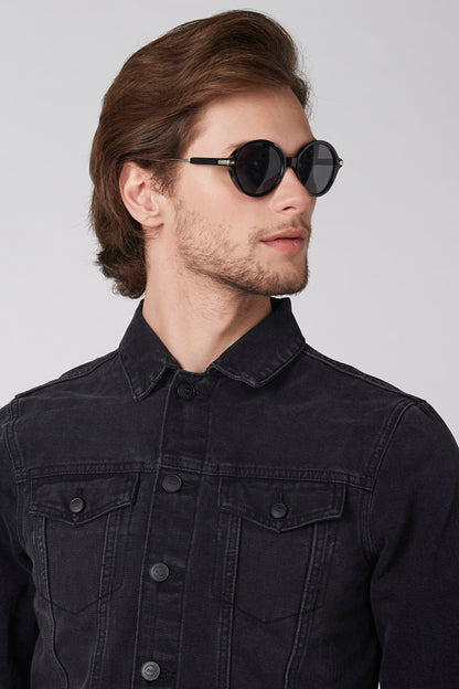 Black denim jacket close-up with buttoned collar and flap chest pockets.