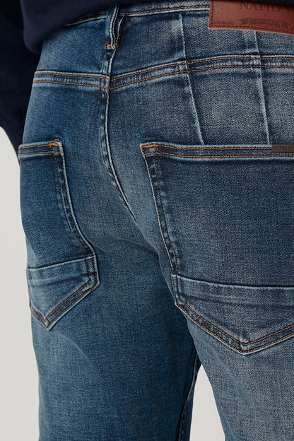 Close-up of blue denim jeans seams, stitched back pockets, and coin pocket