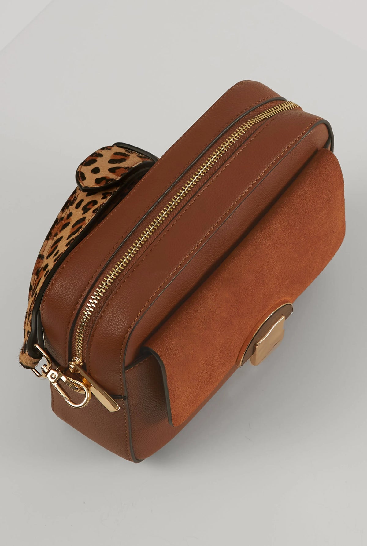 Brown leather crossbody bag side view with gold zipper and leopard-print strap panel