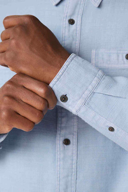 Light blue shirt sleeve cuff with dark buttons and buttoned placket detail