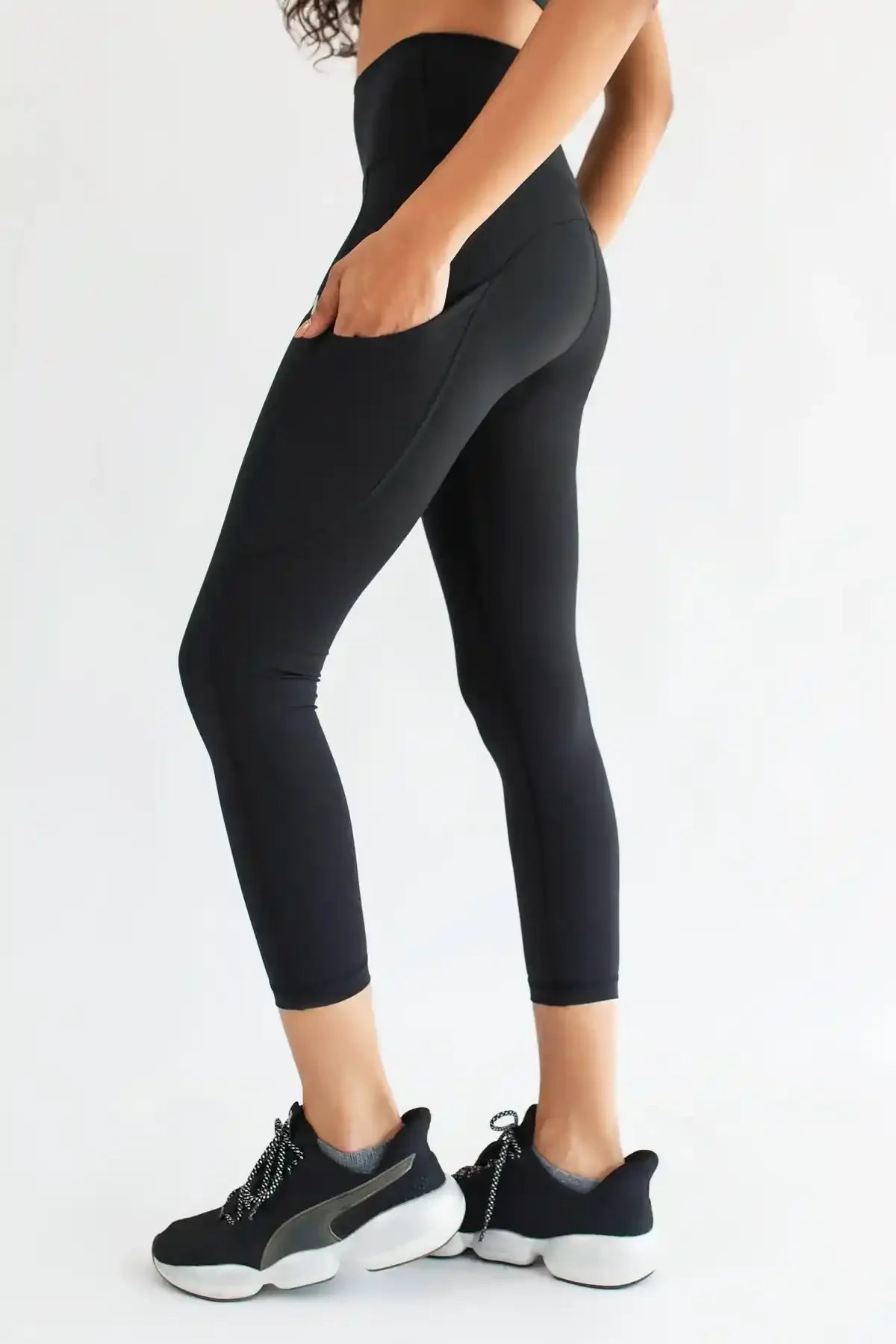 Black cropped leggings with subtle side logo and close-up of fitted leg