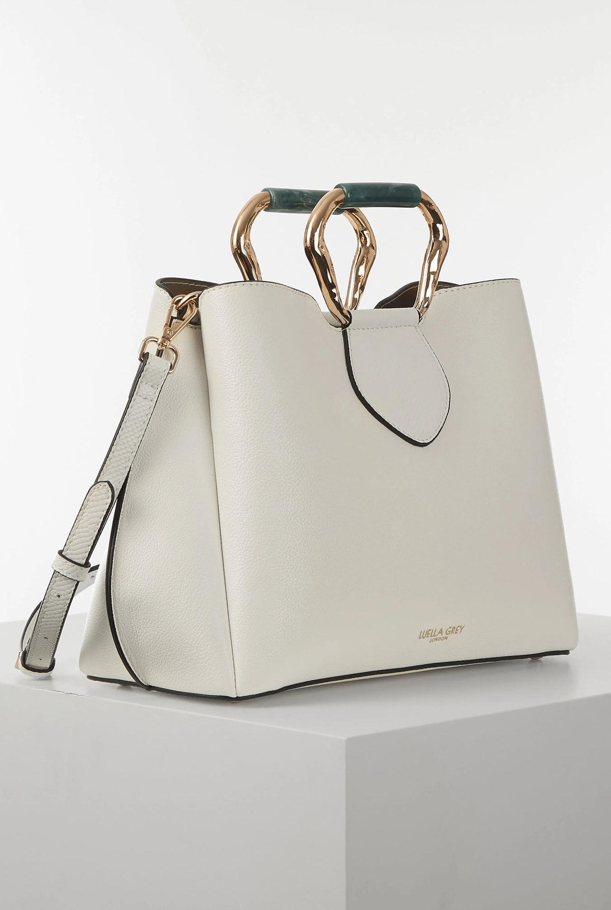 White handbag with wide top handle, gold-tone rings, and long shoulder strap