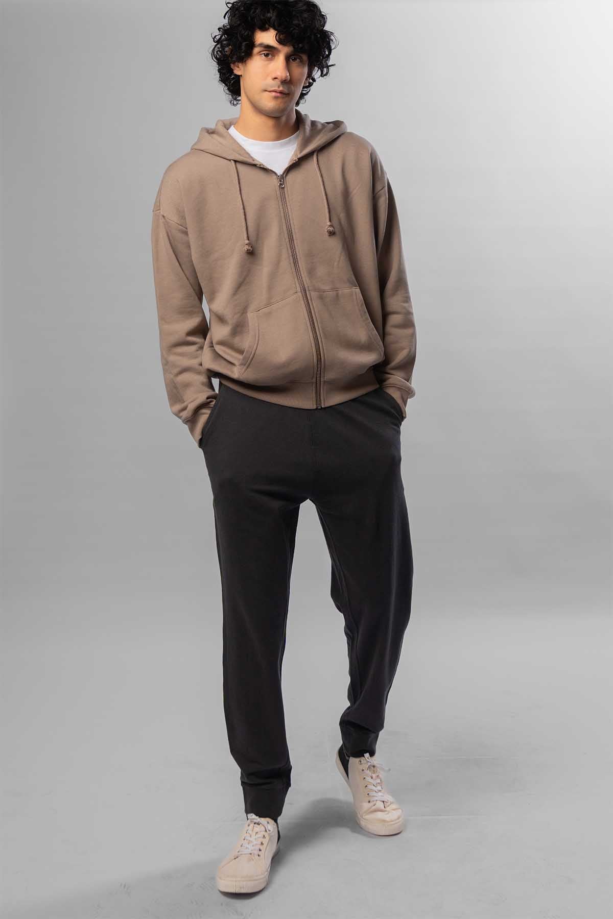 Men's taupe zip-front hoodie with hood and drawstrings, worn with black jogger pants