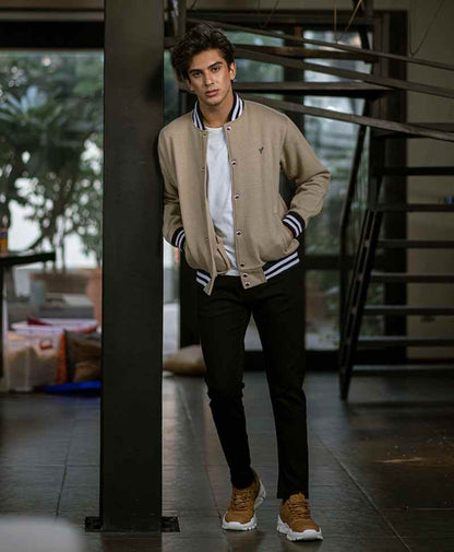 Men's tan fitted bomber jacket with striped ribbed cuffs, snap-front and chest logo