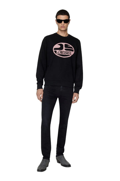 Black denim jeans on model, full-length view with rolled cuffs