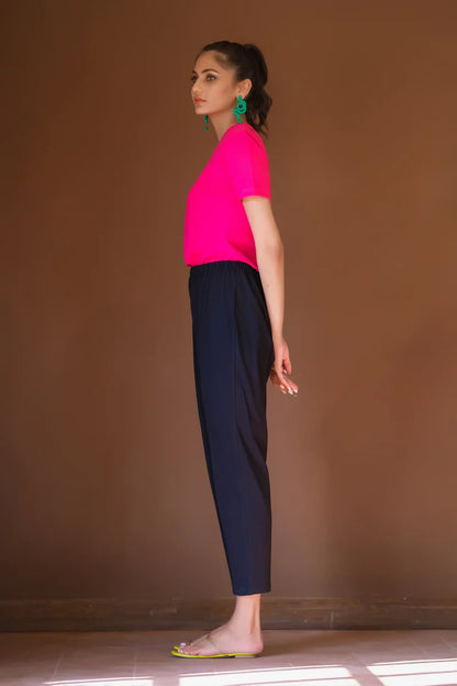 Womenâ€™s fuchsia short-sleeve blouse with dark navy fitted pants, side view
