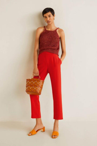 Coral red sleeveless knit top and high-rise ankle-length trousers