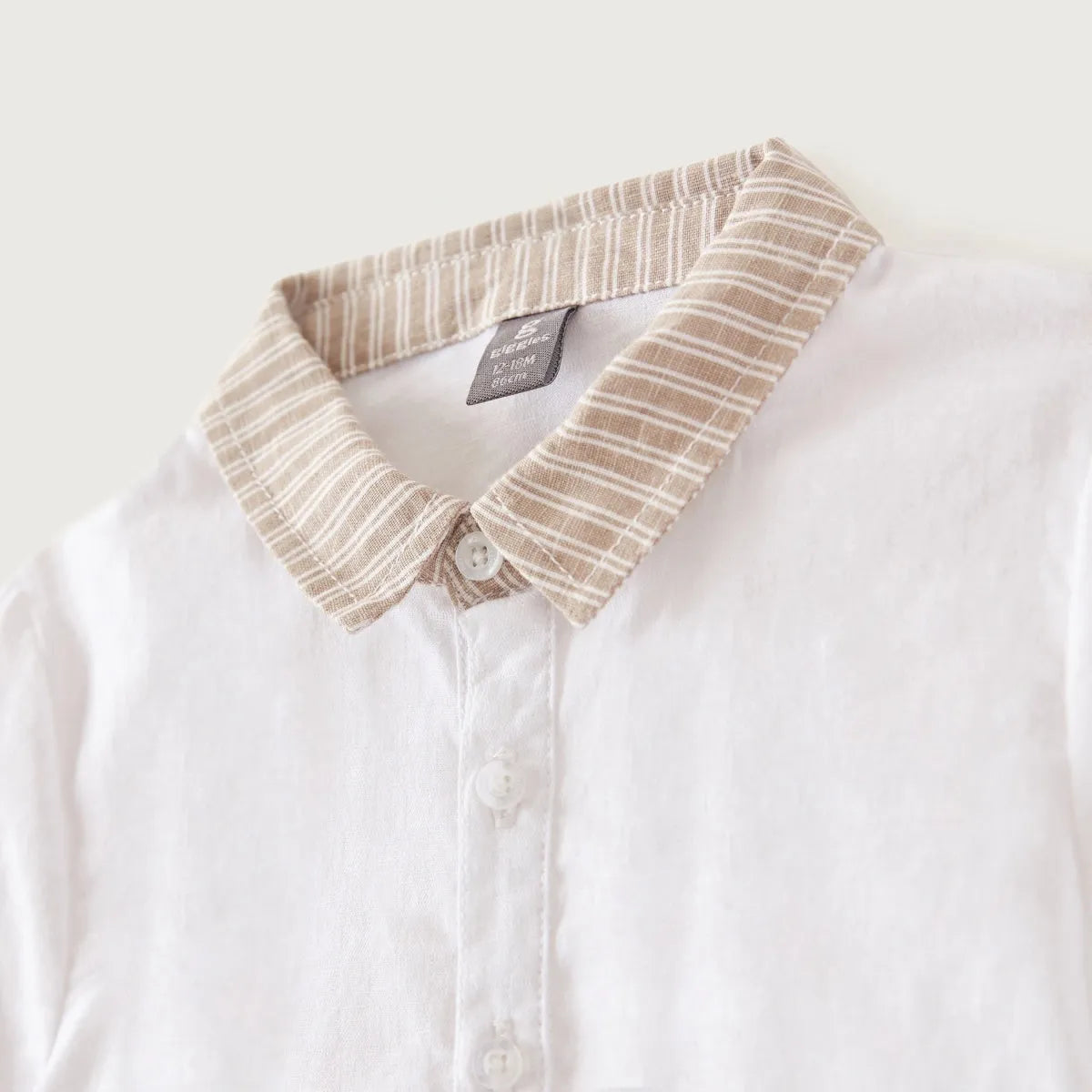 White baby shirt close-up: striped collar trim and button placket