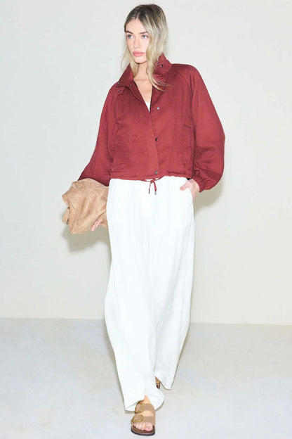 White wide-leg trousers with drawstring waist, paired with burgundy button shirt