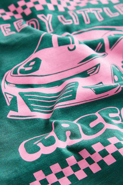 Close-up of teal fabric with pink race car graphic and checkered banner print