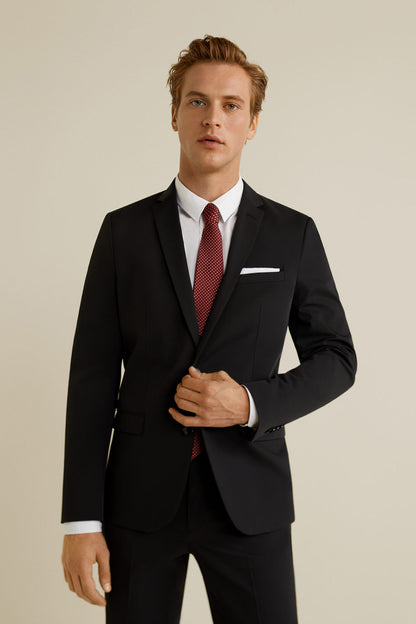 Men’s black suit jacket with white shirt, red patterned tie, and pocket square