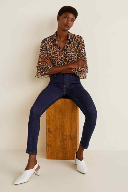 Leopard-print V-neck blouse and dark blue slim jeans with white slip-on shoes