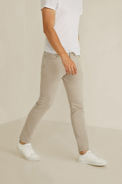 Beige denim jeans with cuffed hems, front zipper, and five-pocket styling