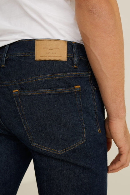 Dark blue denim jeans back pocket with stitched seams and logo patch