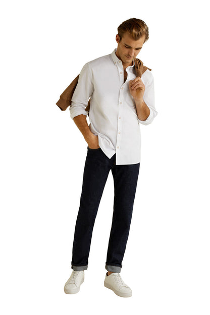 White button-up shirt worn with dark jeans and white sneakers, long sleeves