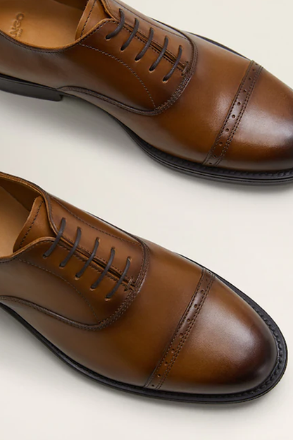Close-up of brown leather lace-up oxford shoes with black sole