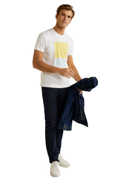 White crew-neck T-shirt with yellow chest graphic, styled with dark jeans