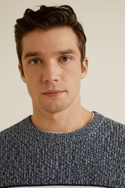 Close-up: dark crewneck knit sweater with white and navy stripe bands