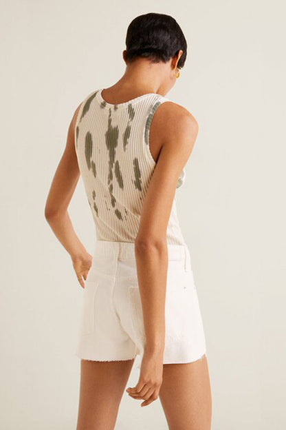 White sleeveless top with green print on back; white high-rise shorts with frayed hem
