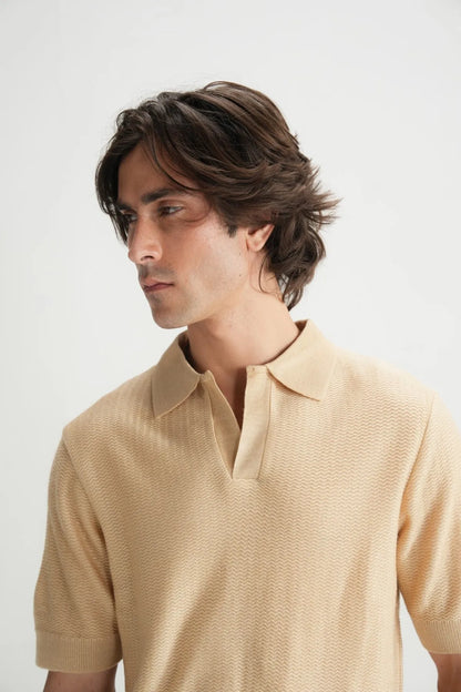 Beige polo shirt collar detail with short sleeves and textured knit fabric.
