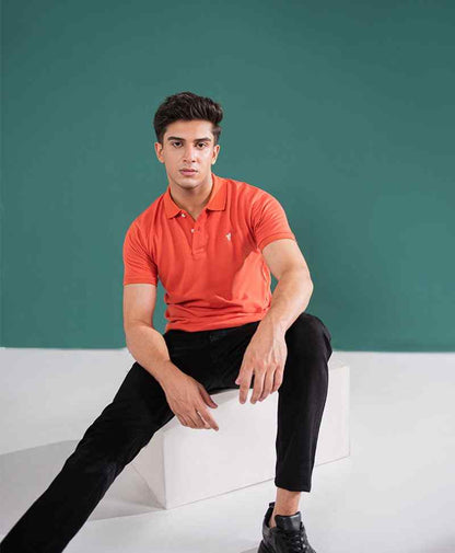 Orange fitted polo shirt with collar and short sleeves, paired with black pants