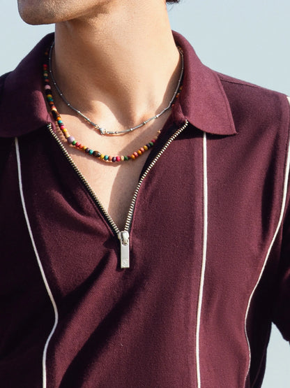 Burgundy polo shirt close-up with silver zipper, contrast piping, spread collar