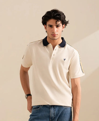 Fitted off-white polo shirt with navy collar, three-button placket, and side sleeve trim.