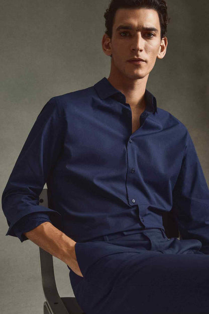 Dark navy button-up shirt worn, long sleeves with buttoned cuffs