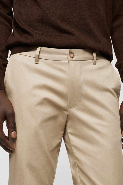 Beige chino pants close-up of front waistband, belt loops, and fly button
