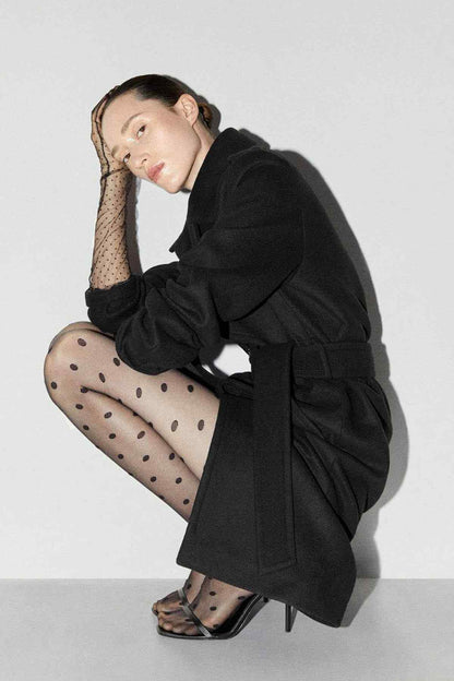 Black sheer polka-dot tights worn by model with black top and sandals