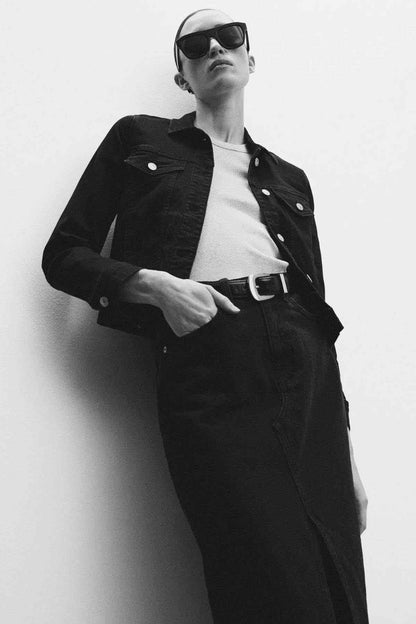 Black denim jacket on model, showing buttoned front and two chest flap pockets.