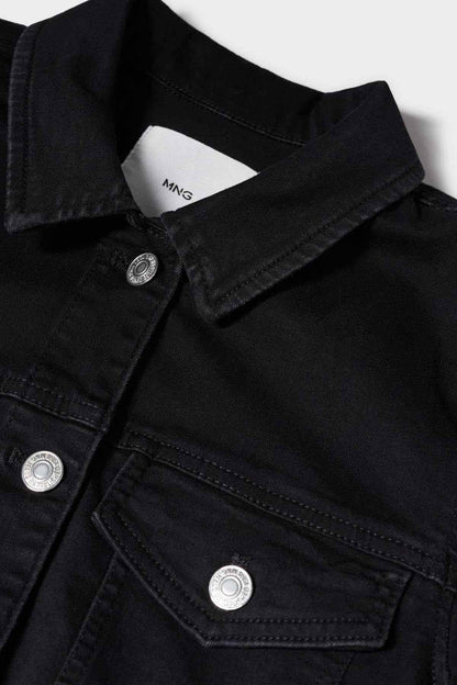 Black denim jacket close-up: collar label, snap buttons, and pocket stitching.