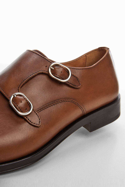 Brown leather double-buckle loafer detail with metal ring buckles and stitching