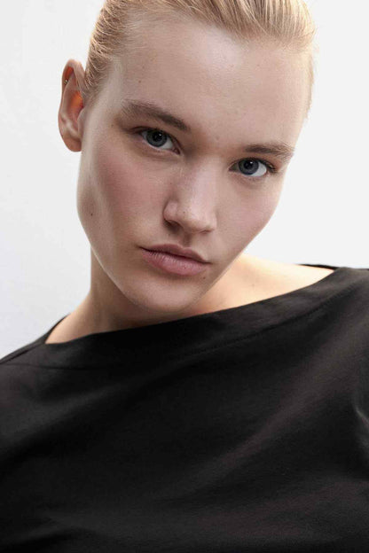 Black long-sleeve crew-neck top, fabric drape close-up