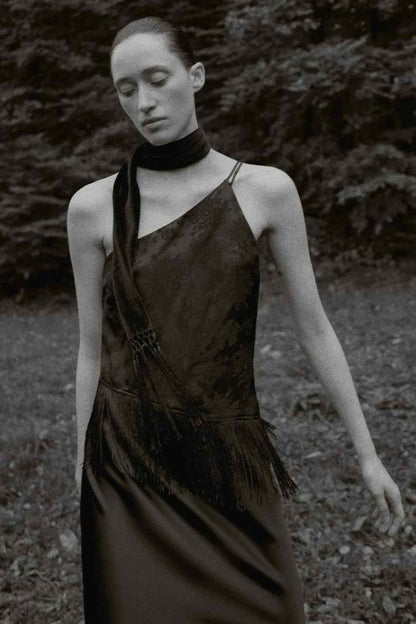 Black sleeveless one-shoulder jumpsuit with fringe hem, angled front