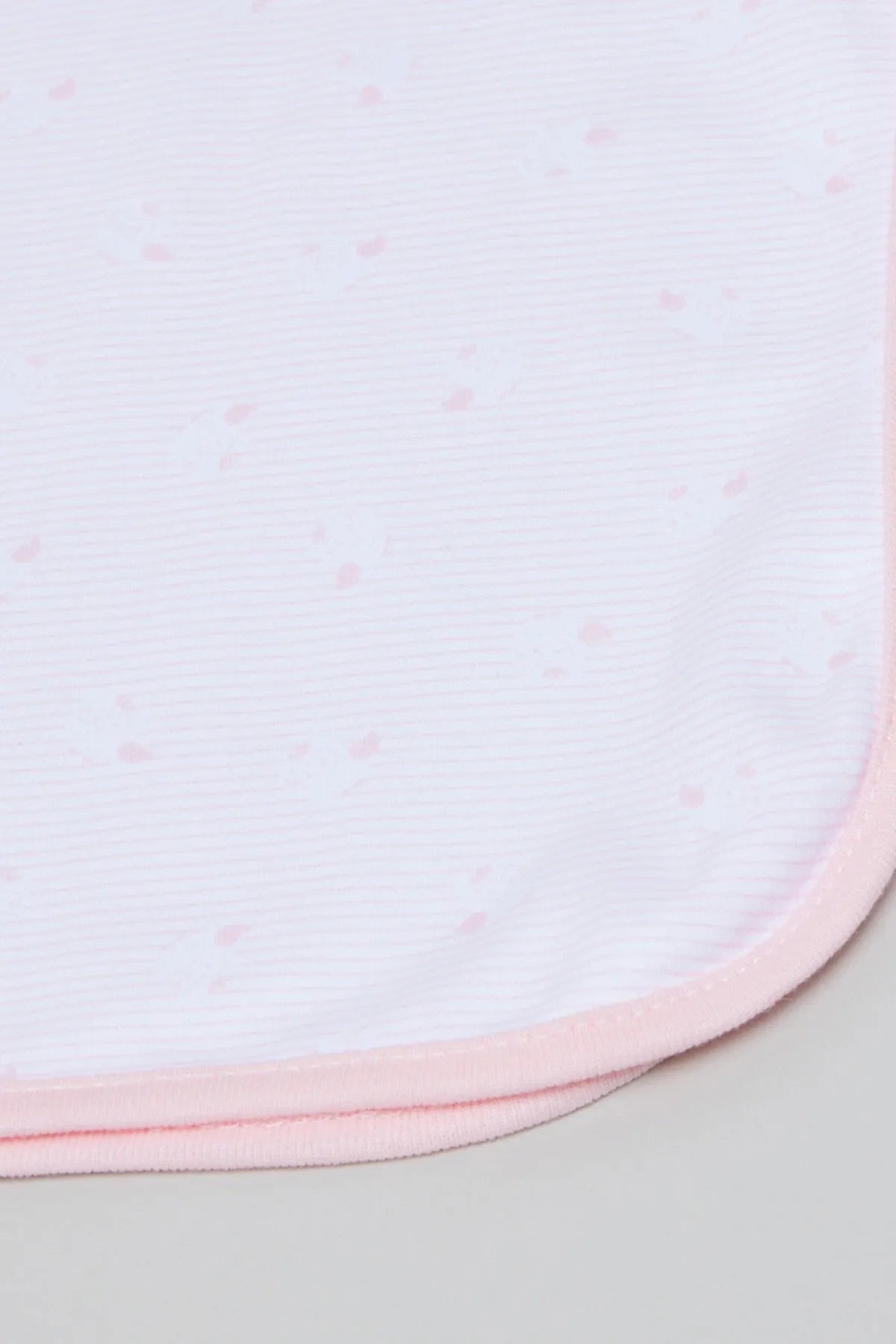 Light pink baby blanket close-up with tiny dots and stitched hem edge