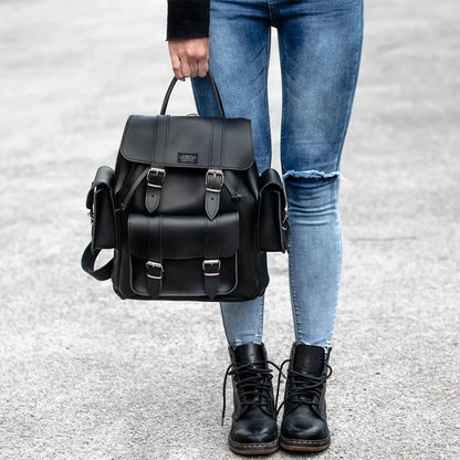 Black flap-top backpack held by a handle with front buckled pockets