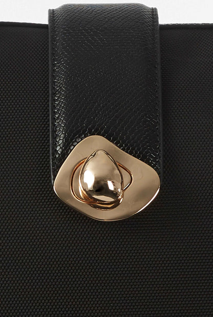 Gold clasp on textured black leather tote bag front panel