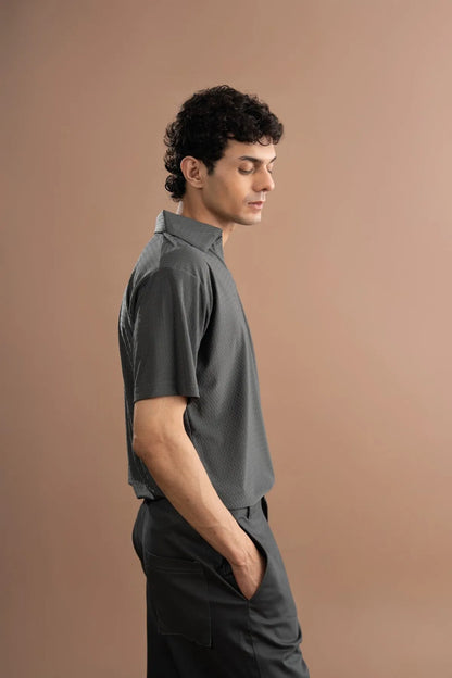 Men's grey short-sleeve button-up shirt with pointed collar; dark trousers